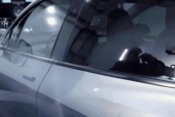 A technician applies ceramic coating to the side of a silver car using a soft microfiber towel, revealing a deep, reflective gloss as the product bonds to the paint surface.