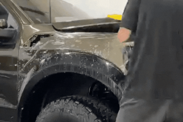 Close-up of a technician applying clear paint protection film to a white car at Hi-Tech Auto Spa in Savannah, GA. The film acts as a transparent barrier against chips, scratches, and UV damage, helping preserve the car’s factory finish.